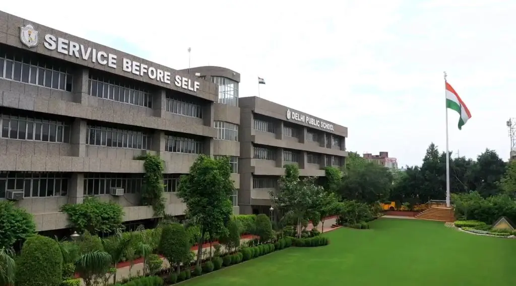 "Campus view of Delhi Public School with lush green lawn, Indian flag, and school building — one of the top schools in Faridabad."